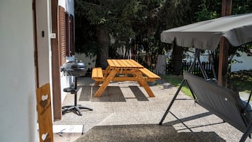 Un espace extérieur abrité, équipé d’une table de pique-nique et d’un barbecue.