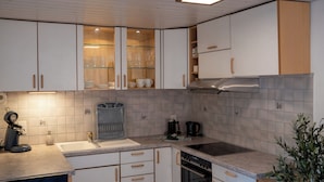 Ett modernt kök med vita skåp, en rostfri köksfläkt och en inbyggd diskmaskin.
