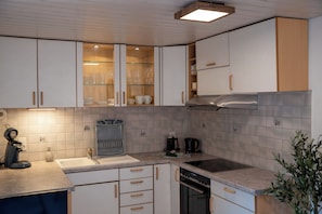 A modern kitchen with white cabinets, a stainless steel range hood, and a built-in dishwasher. - Alpenwohnung in Laax Garten, Bergblick & Parkplatz (Laax)
