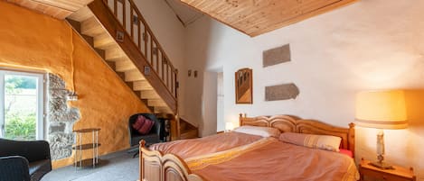 Un dormitorio con una cama de madera, una mesita de noche, una lámpara, una silla, un escritorio y una escalera.