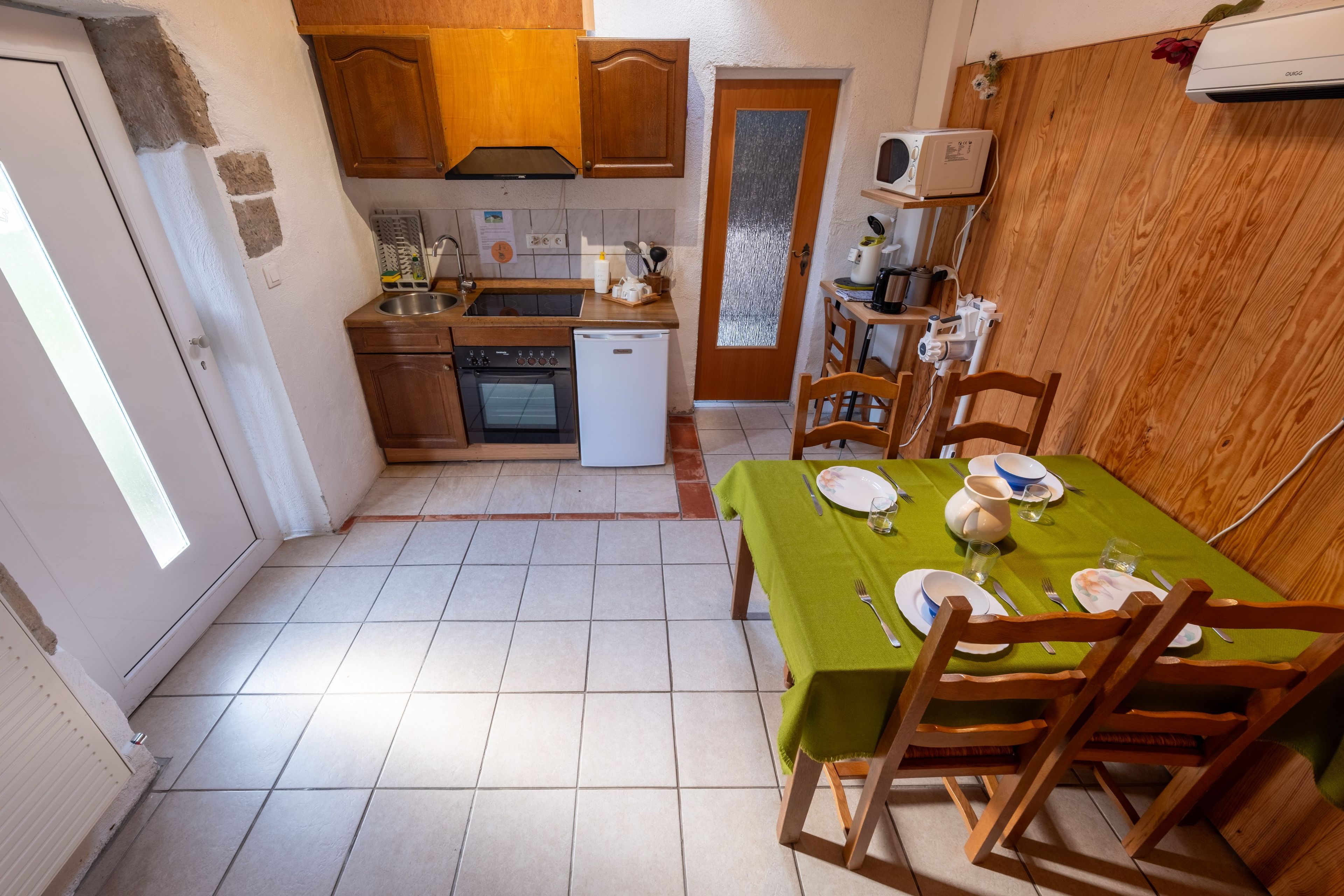 A compact kitchen with a dining area, including a table set for two with plates, glasses, and cutlery.