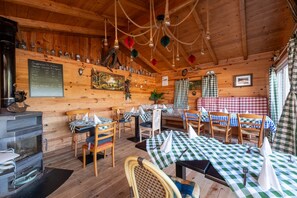 A rustic wooden interior with tables and chairs, a fireplace, and a menu board. - Maison Principale Apartment: Mountain View, Private Terrace, and Wi-Fi (Xertigny)