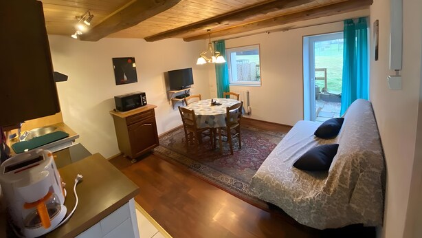 A cozy room with a dining area, a sofa, a coffee machine, and a television. - Apartment 'Maison Du Bonheur - Appartement' with Mountain View, Private Terrace and Wi-Fi (Xertigny)