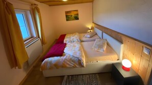 A bedroom with a bed, a bedside lamp, a window, and a painting on the wall. - Apartment 'Maison Du Bonheur - Appartement' with Mountain View, Private Terrace and Wi-Fi (Xertigny)