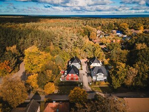 An aerial view of a residential area with two prominent houses, surrounded by dense forest and a clear sky. - Holiday Home With 3 Bedrooms (Ostseebad Prerow)