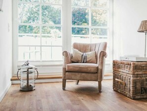 A room with a large window, a cushioned armchair, a wicker basket, and a floor lamp. - Holiday Home With 3 Bedrooms (Ostseebad Prerow)