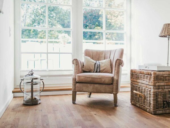 A room with a large window, a cushioned armchair, a wicker basket, and a floor lamp. - Holiday Home With 3 Bedrooms (Ostseebad Prerow)