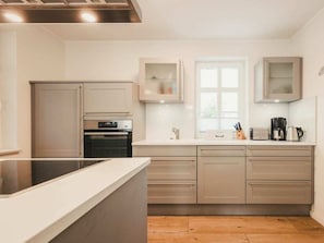 A modern kitchen with a central island, built-in oven, and a window providing natural light. - Holiday Home With 3 Bedrooms (Ostseebad Prerow)