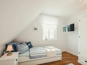 A bedroom with a bed, a nightstand, a lamp, a window, and a wardrobe. - Holiday Home With 3 Bedrooms (Ostseebad Prerow)