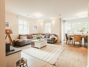 A living room with a sofa, coffee table, and dining area with chairs and a table. - Holiday Home With 3 Bedrooms (Ostseebad Prerow)