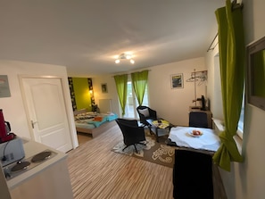 Ein kleines Hotelzimmer mit Bett, Schreibtisch, Stuhl und Nachttisch.