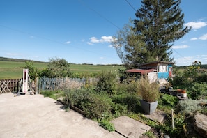 A rural property with a wooden fence, a small shed, and a large tree.