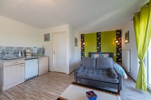 Un espace de vie compact comprenant un coin cuisine, un canapé et une table à manger.
