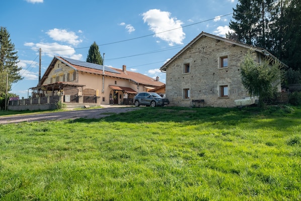 A stone building with a car parked in front, surrounded by a grassy area and trees.