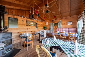 Een rustiek houten interieur met tafels en stoelen, een open haard en een menukaart.