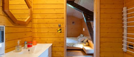 Ein Interieur einer Holzhütte mit Bad, einem Bett und einem kleinen Tisch.