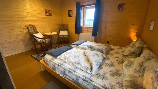 A cozy room with a bed, two chairs, a small table, and a window with curtains. - Guest Room "Double Room - Petit moulin" with Mountain View, Shared Terrace and Wi-Fi (Xertigny)