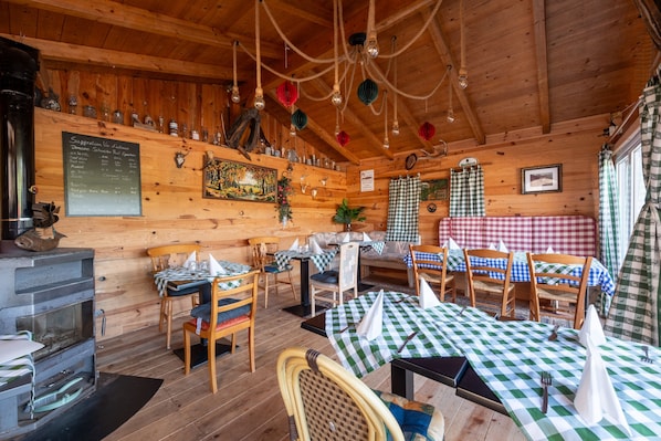 Un interior rústico de madera con mesas, sillas, una chimenea y una pizarra con el menú.