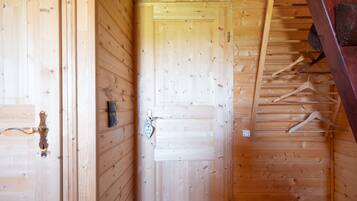Een houten interieur met een deur, een kapstok en een ophangende jas.