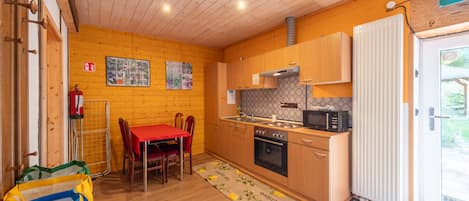 Eine kompakte Küche mit Holzschränken, einer Mikrowelle und einem roten Tisch mit Stühlen.