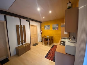 A modern kitchen with wooden cabinets, a dining area with a table and chairs, and a yellow accent wall with artwork. - Bed and Breakfast 'Chambre Double - Petite Vache' with Mountain View, Shared Terrace and Wi-Fi (Xertigny)
