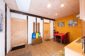 A wooden interior with a dining area, a kitchen, and a door with a number.