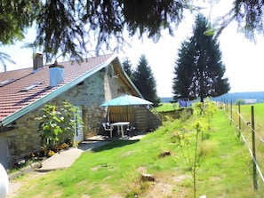 A stone house with a tiled roof, a wooden deck, and a small table with chairs. - Bed and Breakfast 'Chambre Double - Petite Vache' with Mountain View, Shared Terrace and Wi-Fi (Xertigny)