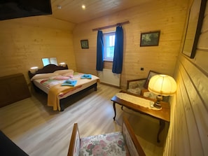 A wooden-paneled room with a bed, a chair, a table, and a window with curtains. - Bed and Breakfast 'Chambre Double - Petite Vache' with Mountain View, Shared Terrace and Wi-Fi (Xertigny)