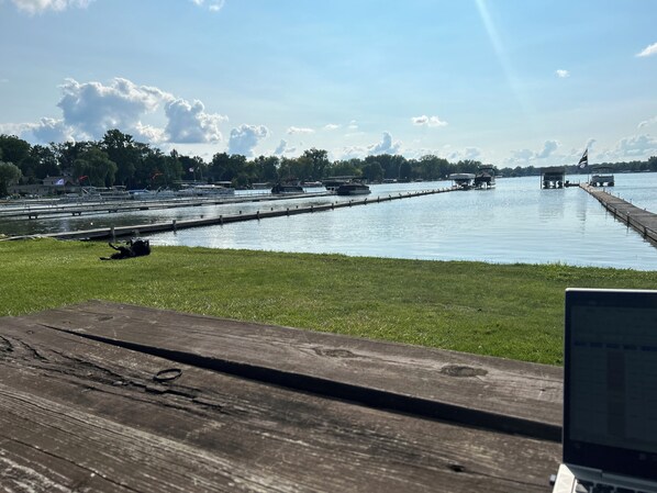 Uitzicht op een meer met een houten steiger, boten en een gazon.