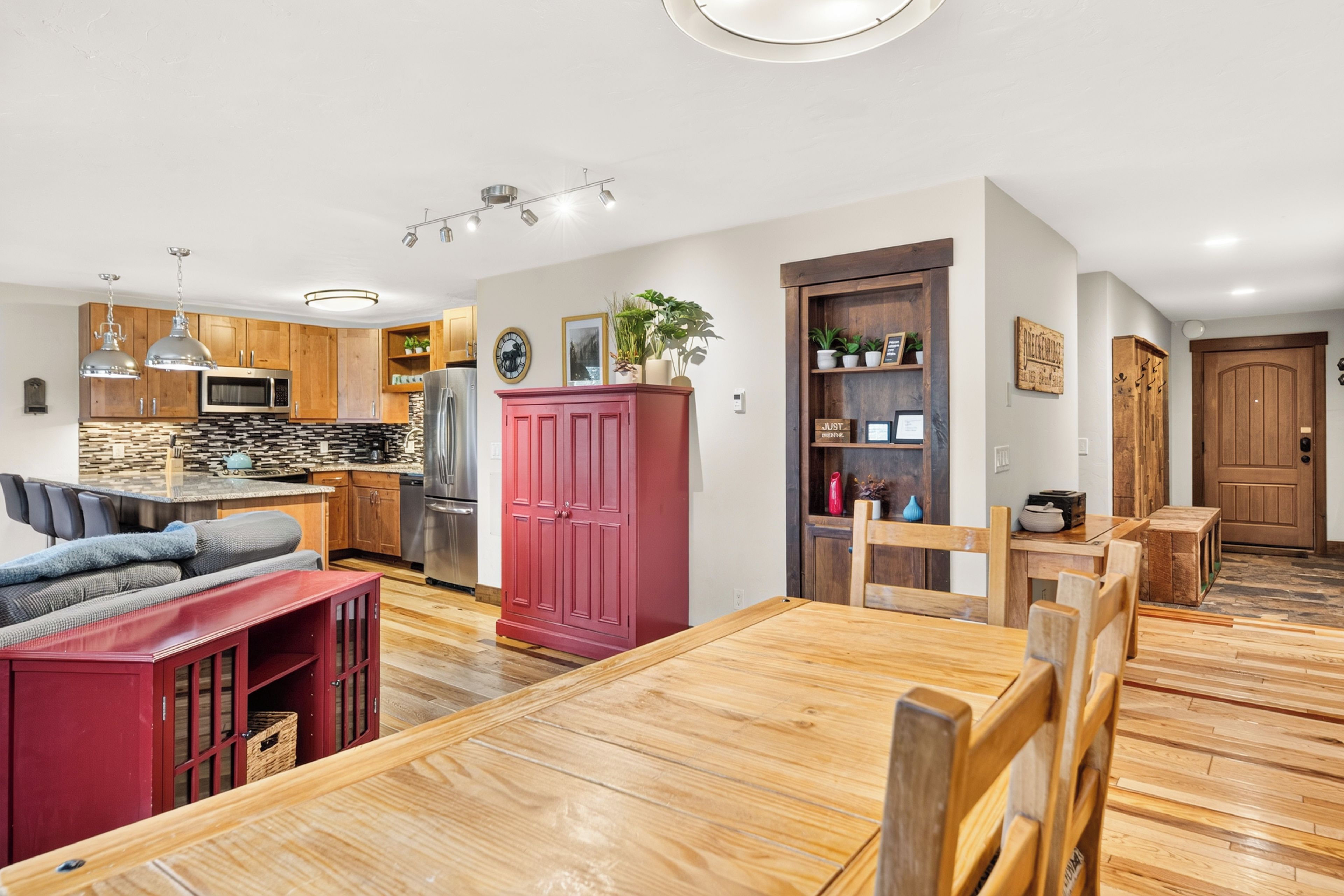 Eine moderne Küche mit Holzschränken, einem roten Schrank und einem Essbereich mit Holztisch und Stühlen.