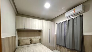 Een slaapkamer met een bed, een kledingkast, een airconditioning en een gordijn.
