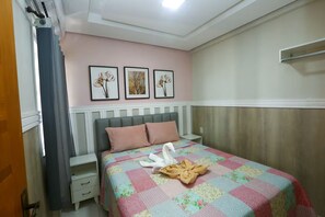 Ein Schlafzimmer mit einem Bett, einem Nachttisch, einer Kommode und einer Wand mit drei gerahmten Bildern.