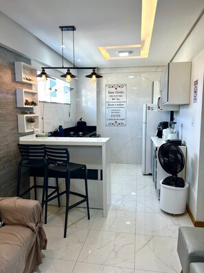 Une cuisine moderne dotée d’un îlot central, de tabourets de bar et d’un réfrigérateur encastré.