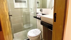 Een badkamer met een douchecabine van glas, een toilet, een wastafel en een spiegel.
