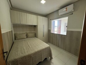 Ein Schlafzimmer mit Bett, Fenster und integriertem Kleiderschrank.