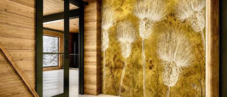 A modern interior with wooden paneling, a glass door leading outside, and a textured wall with a floral pattern.