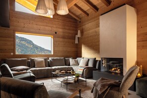 Un salon confortable avec une grande fenêtre, une cheminée et un ensemble de canapés.
