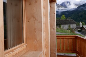Ein Holzbalkon mit Blick auf einen Berg und ein traditionelles Gebäude im Hintergrund.