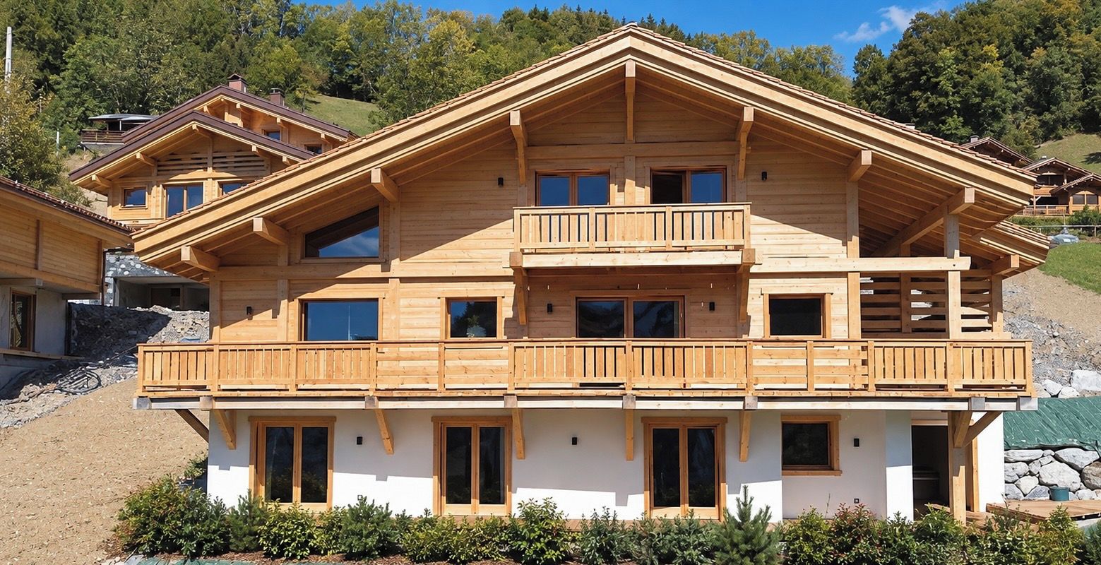 Een chalet met meerdere verdiepingen, houten balkons, grote ramen en een stenen fundering.