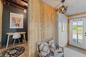 A room with a wooden wall, a white door with a view, a framed picture, a white chair, and a patterned rug. - Private Western Desert Retreat Horses Welcome (Maricopa County)