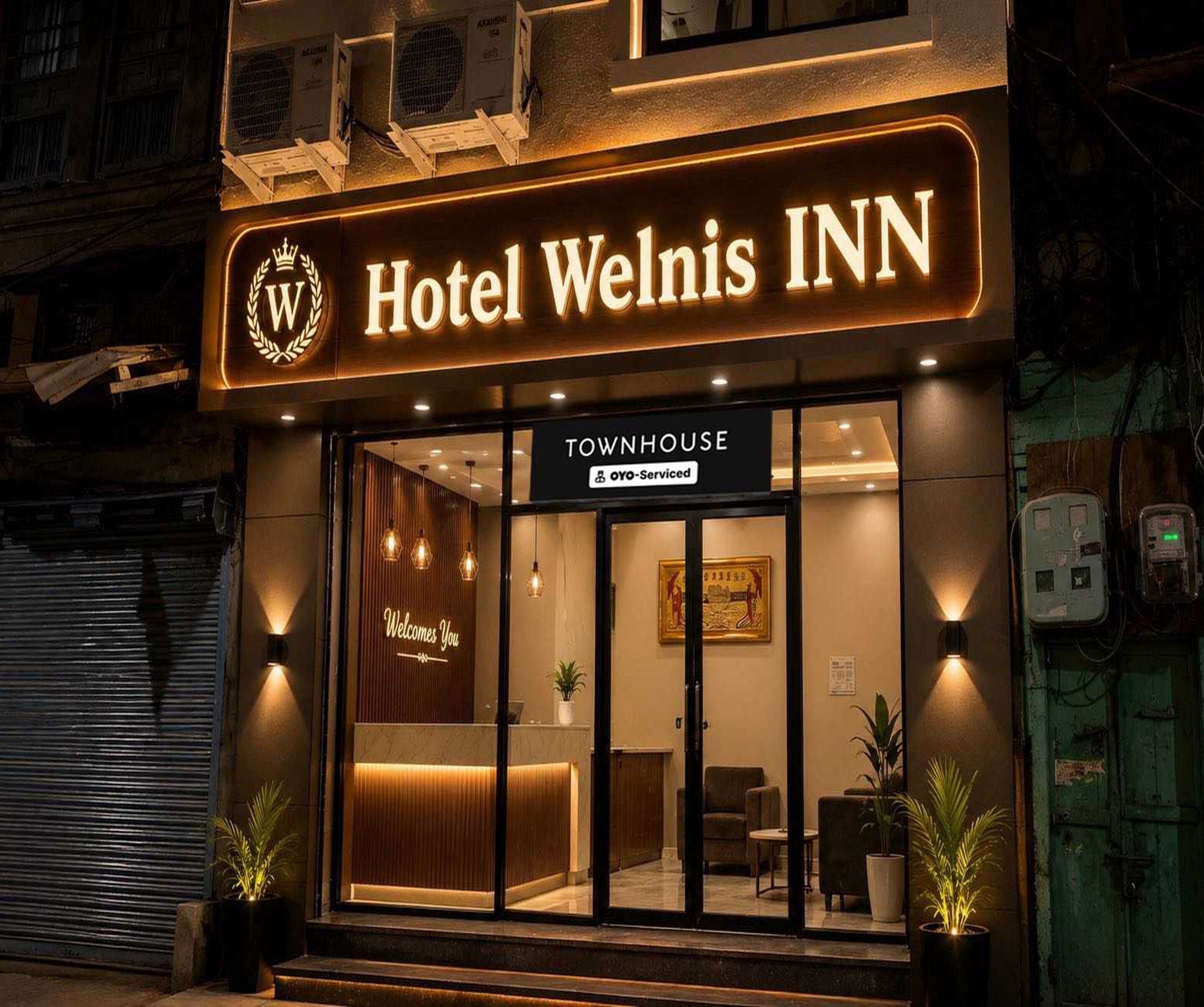 Hotel Welnis Inn mit einem 'Townhouse'-Schild, einer Rezeption mit einem 'Welcome You'-Schild und einem modernen Innenarchitekturstil.