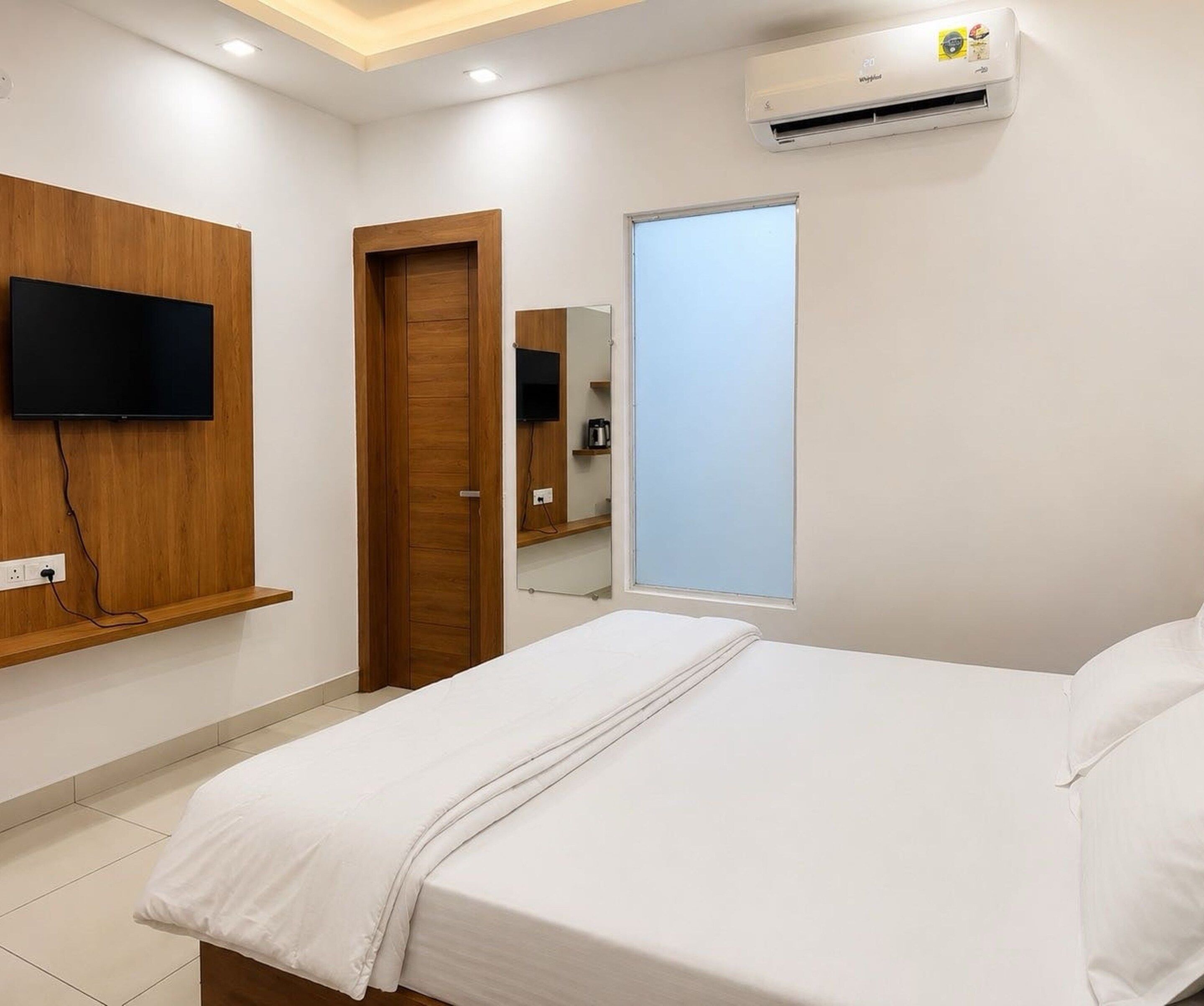 Ein Hotelzimmer mit Bett, Wandfernseher, Tür und Klimaanlage.