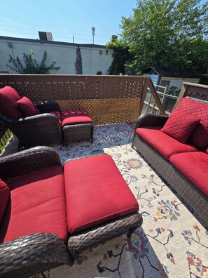 A rooftop patio with wicker furniture and red cushions. - Comfy 5 bedroom home conveniently located (St. Catharines)