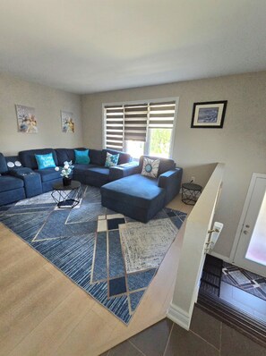 A living room with a sectional sofa, ottoman, and a patterned rug. - Comfy 5 bedroom home conveniently located (St. Catharines)