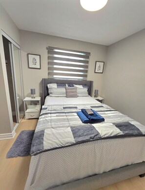A bedroom with a large bed, a bedside table, a lamp, and a framed picture on the wall. - Comfy 5 bedroom home conveniently located (St. Catharines)