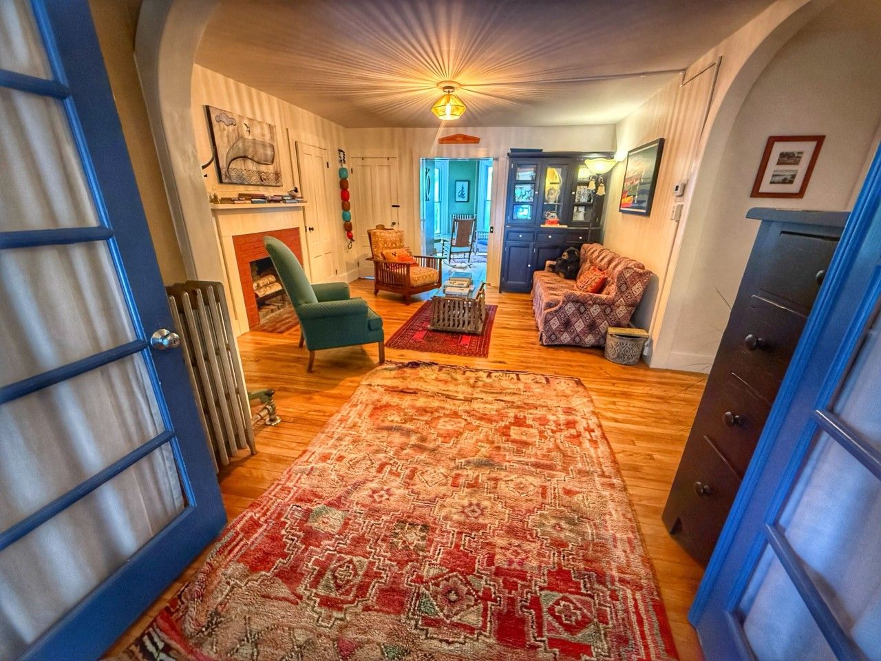 Una sala acogedora con chimenea, un tapete estampado y una puerta azul.