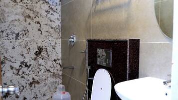 A bathroom with a toilet, sink, shower, and towel rack.
