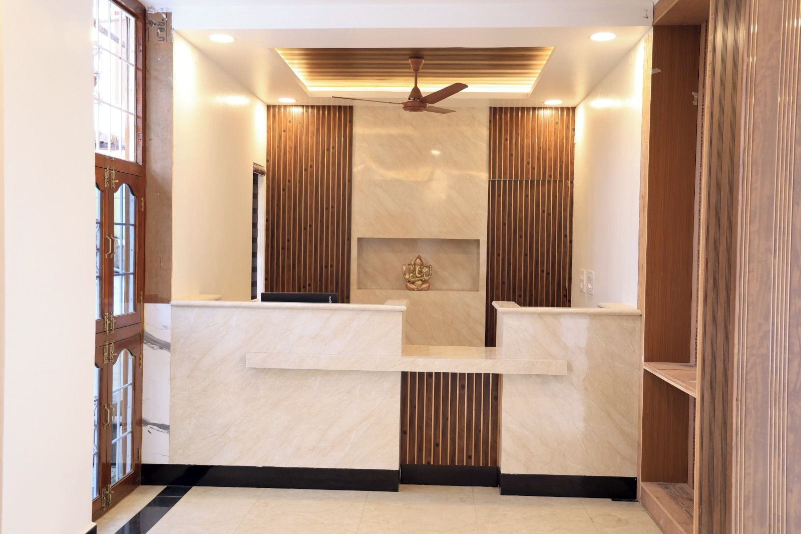 A reception area with a marble counter, wooden paneling, a ceiling fan, and a decorative item on the wall.