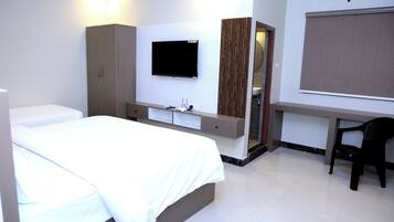 A hotel room with a bed, a desk, a chair, a TV, and a wardrobe.