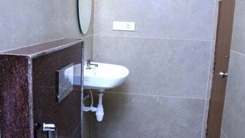 A bathroom with a toilet, two sinks, a mirror, and a towel rack.